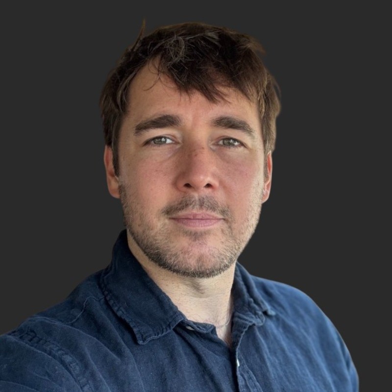 Portrait of Joshua Farrow smiling with a blurred outdoor background